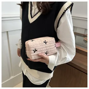 Detail of pink quilted makeup bag with black bow embroidery and fabric carry handle