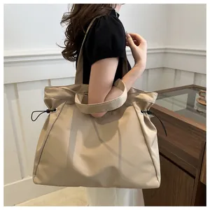 Detail view of khaki nylon tote bag featuring adjustable side drawstrings and double handles