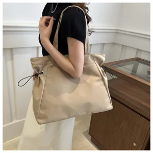 Detail view of beige nylon tote bag with drawstring side and stylish shoulder strap