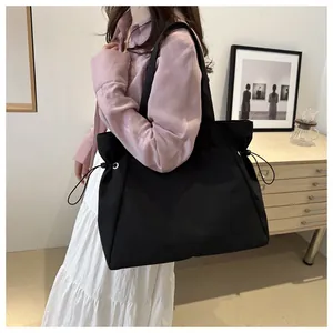 Detail of a large black tote bag showing the functional drawstring and side metal eyelets