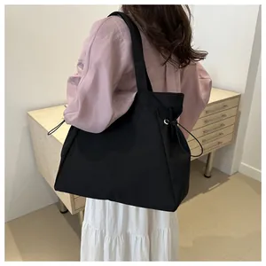 Detail of black tote bag featuring metallic ring and adjustable drawstring closure