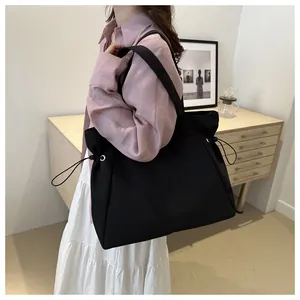Detail view of large black nylon tote bag with side drawstring and reinforced shoulder strap