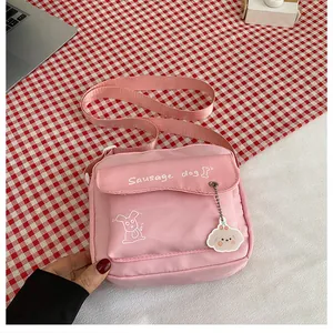 Détail d'un sac bandoulière en toile rose avec imprimé teckel sur nappe à carreaux