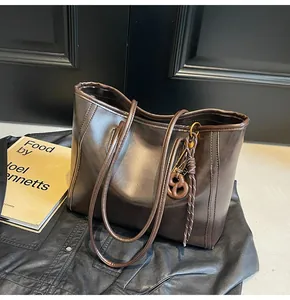 Detail of dark brown leather tote bag with unique figure-eight ornament and woven pendant