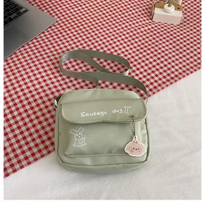 Détail du sac bandoulière en toile vert clair avec motif chien mignon et breloque rose
