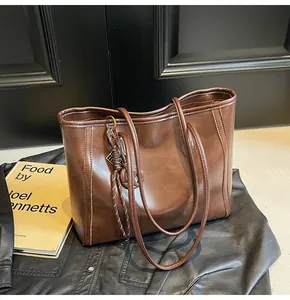 Detail of dark brown faux leather tote bag with decorative knot and long shoulder straps