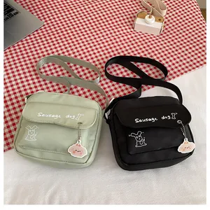 Détail de sacs à bandoulière en nylon noir et vert menthe avec breloque nuage
