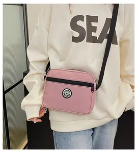 Pink nylon crossbody bag with black SPORT logo shown on a model for size and fit guide