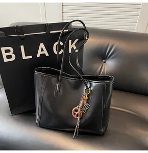 Detail shot of the large black leather tote bag featuring a decorative pretzel charm