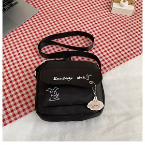 Détail de la sacoche en toile noire avec imprimé teckel et joli pendentif en acrylique