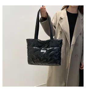 Macro detail of black quilted puffer tote bag with glossy finish and logo tag
