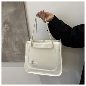 Détail du sac à bandoulière blanc crème avec applique florale et coutures texturées