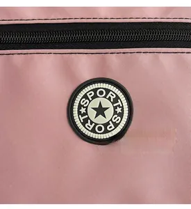 Detail shot of a pink oxford cloth bag showing a star logo patch and black zipper texture