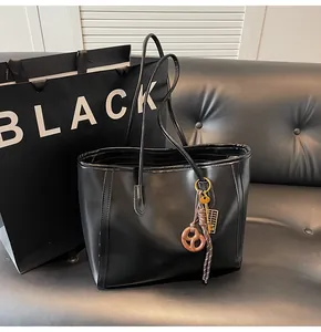 Detail of black faux leather tote bag with vintage resin pendant and keychain accessory