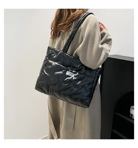 Detail of a black quilted puffer tote bag with a fashion label on a neutral coat