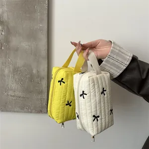 Quilted makeup bags with bow embroidery, available in yellow and cream white