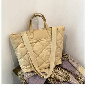 Detail of beige quilted tote bag showing large diamond stitching and wide shoulder strap