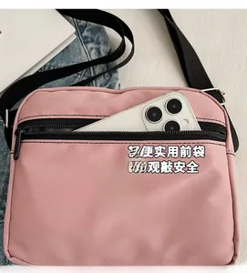 Detailed view of pink nylon crossbody bag with black zipper and adjustable shoulder strap