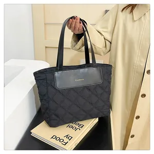Close-up of black quilted nylon tote bag with fashion patch and slim handles