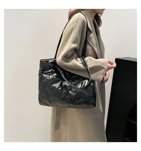 Detail of glossy black quilted tote bag with FASHION label and long shoulder straps
