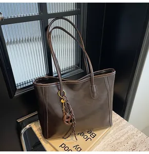 Detail view of a vintage dark brown faux leather tote bag with stylish decorative pendant