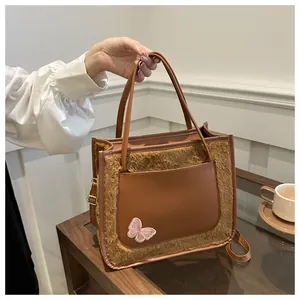 Détail du sac fourre-tout en peluche marron avec broderie papillon rose et bandoulière