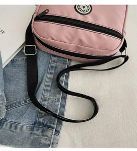Flat lay of pink nylon crossbody bag with adjustable strap and casual star logo details