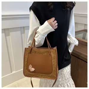Détail du sac cabas en peluche marron avec poche en cuir et papillon en paillettes roses