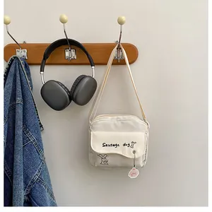 Détail d'un sac bandoulière en toile crème avec illustration de teckel et rabat ondulé