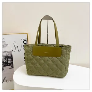 Detail of army green quilted nylon tote featuring a FASHION leather patch and handles