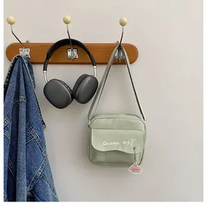 Détail du sac bandoulière en toile vert clair avec imprimé chien et breloque rose