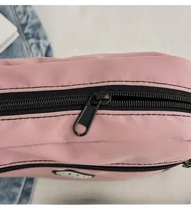 Close-up of smooth black hardware zipper detail on pink nylon oxford crossbody bag
