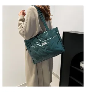 Deep green quilted puffer tote bag with glossy metallic finish shown on model's shoulder
