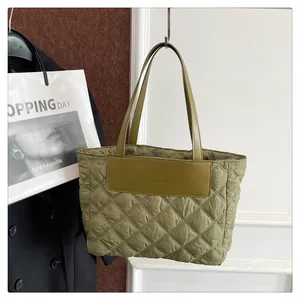 Detail of olive green quilted tote bag with diamond pattern and fashion patch