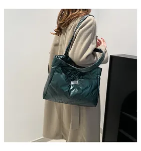 Detail of dark green quilted tote bag showing puffer texture and fashion label