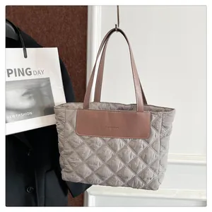 Detail of light gray quilted tote bag with pink leather handles and fashion logo