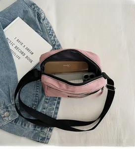 Internal space of pink nylon crossbody bag showing storage for phone and makeup