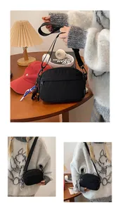 Détails de la sacoche en nylon noir imperméable avec sangle et pendentif décoratif bleu
