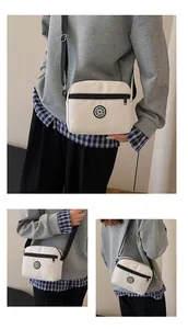 Detail view of cream nylon crossbody bag with circular SPORT logo and black adjustable strap