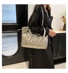 Detail of silver quilted puffer tote bag with fashion tag on a black trench coat