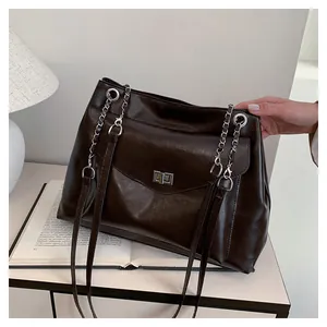 Macro detail of dark brown leather tote bag showing silver chain strap and metal swivel lock