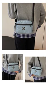 Detailed views of light blue nylon crossbody bag with adjustable black strap and logo