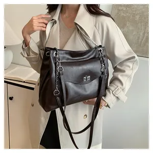 Detail of dark brown faux leather tote bag with silver metal clasp and chain strap