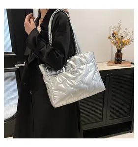 Detail shot of a shiny silver quilted puffer tote bag with a fashion woven label