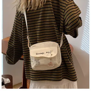 Vue latérale d'un petit sac bandoulière en toile crème avec motif de teckel