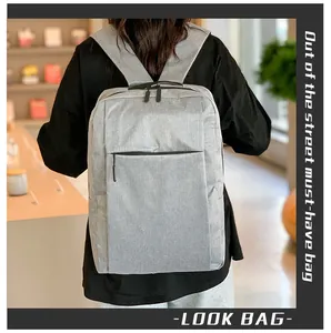 Rear view of a model wearing the light grey minimalist commuter backpack in a lifestyle setting