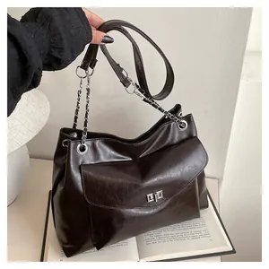 Detail of dark brown tote bag with metal twist lock and chain strap for women