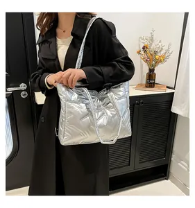 Detail of silver quilted tote bag featuring metallic finish and fashion label on the front