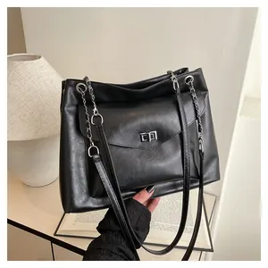 Detail of black textured PU leather tote bag with silver chain strap and metal clasp lock