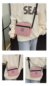 Detailed view of a pink nylon crossbody bag with black zipper and SPORT logo